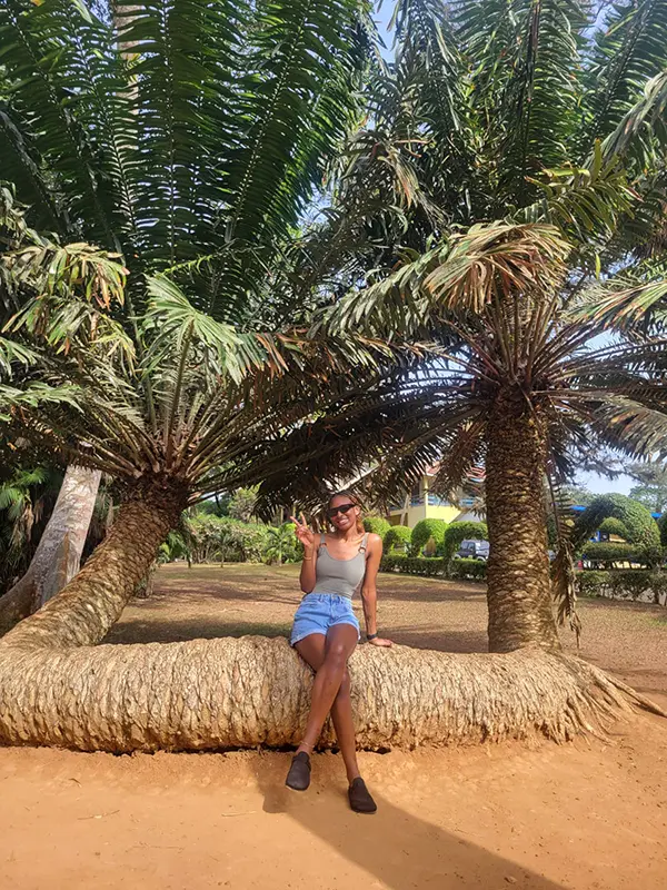 Nadia posing for a picture sitting on a tree in Ghana