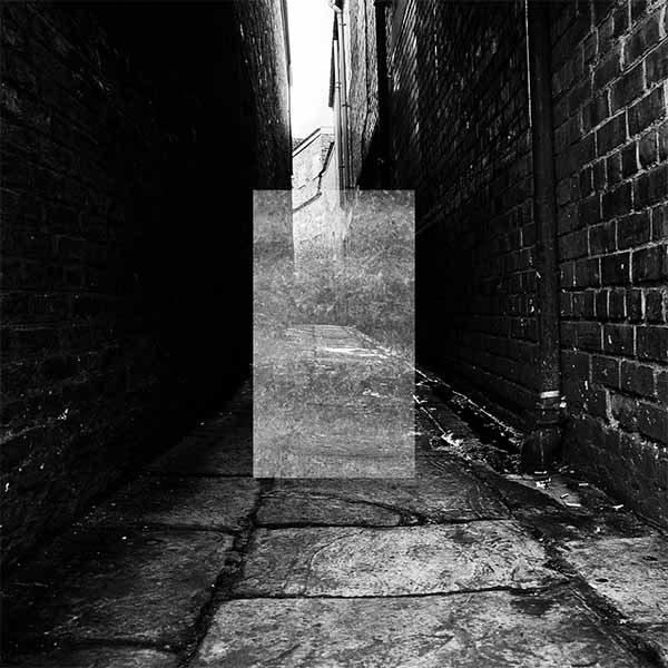 black and white photo of a dark paved alley ways between brick walls with a light grey transparent vertical rectangle in the centre