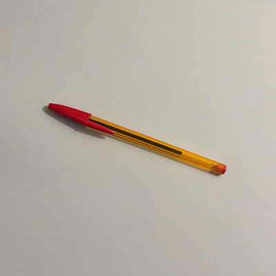 A red ink BIC Cristal pen with a transparent orange barrel