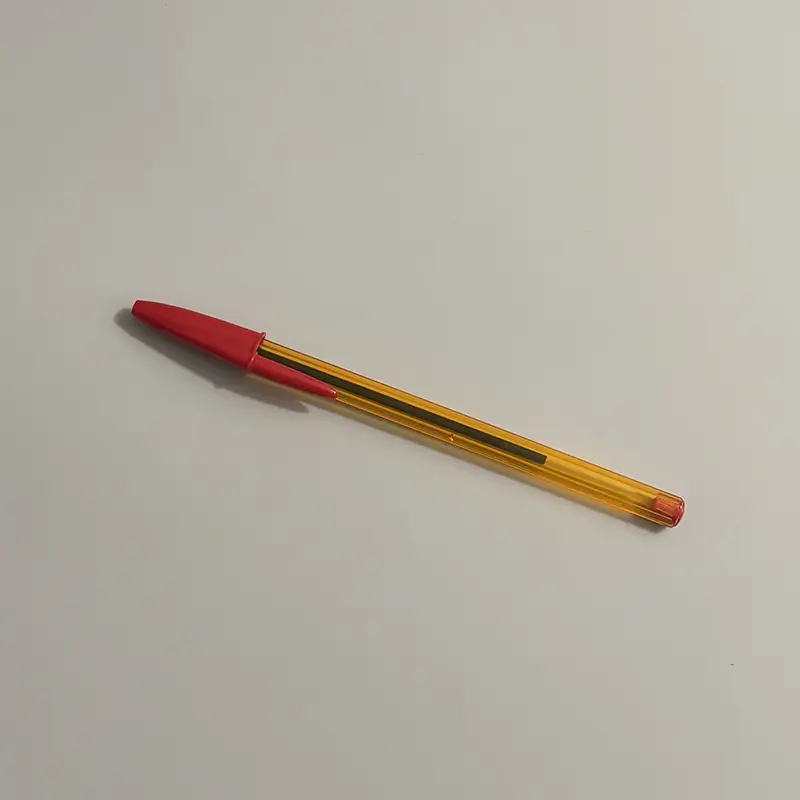 A red ink BIC Cristal pen with a transparent orange barrel