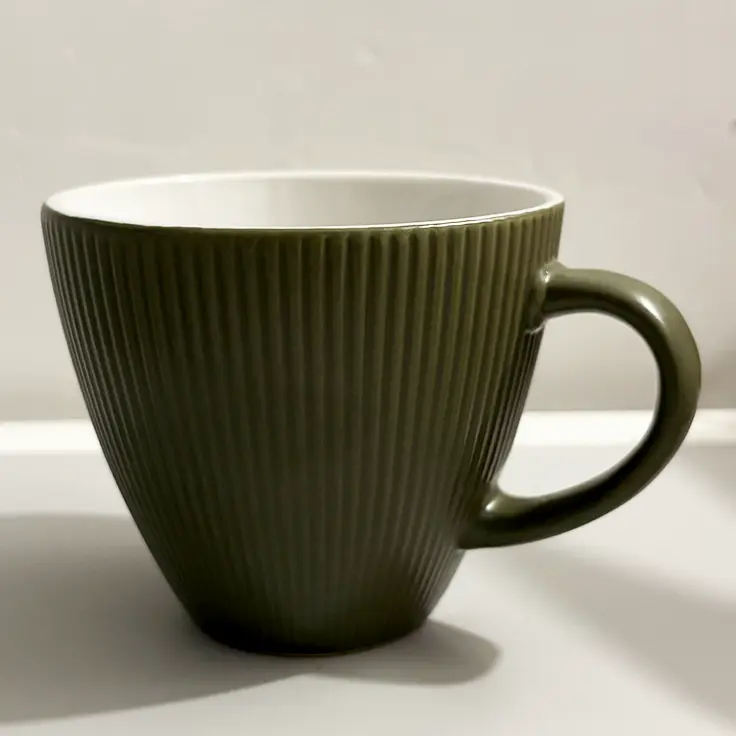A dark green tapered shape ceramic mug with vertical ridges