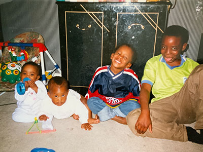 Nadia sitting with her siblings. Nadia is with her twin sister on the left and her 2 older brothers aged 2 and 8 sit on the right